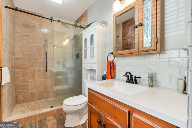 full bathroom with decorative backsplash, a stall shower, toilet, and vanity