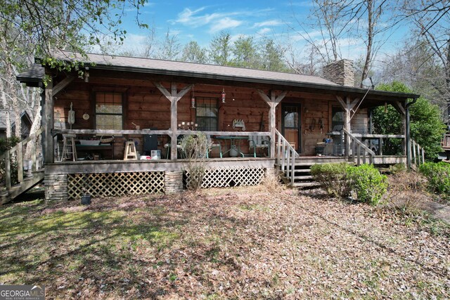 rear view of house featuring a porch and a chimney