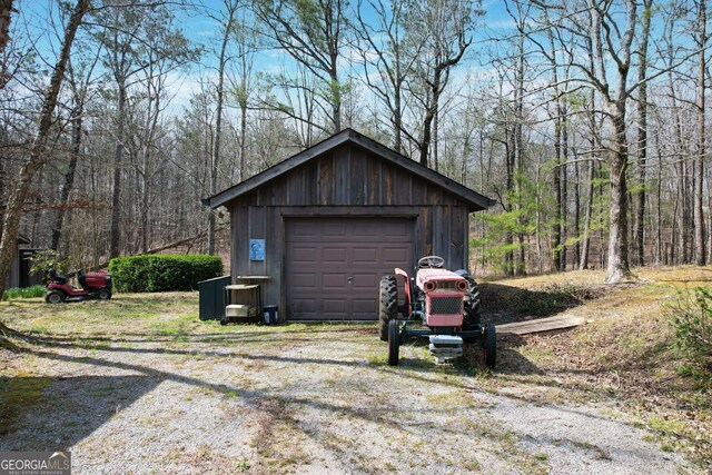 detached garage featuring a view of trees and driveway