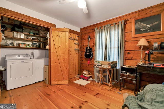 clothes washing area with laundry area, ceiling fan, wood walls, wood-type flooring, and independent washer and dryer