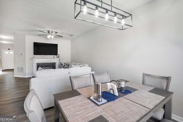 dining area featuring ceiling fan, baseboards, a textured ceiling, and dark wood-style floors