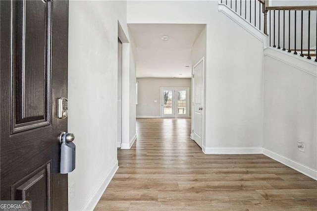 corridor with stairway, light wood-style flooring, and baseboards