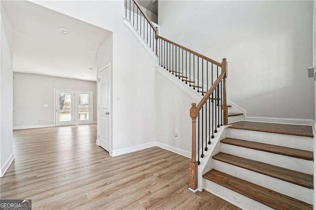 stairs featuring a towering ceiling, baseboards, and wood finished floors