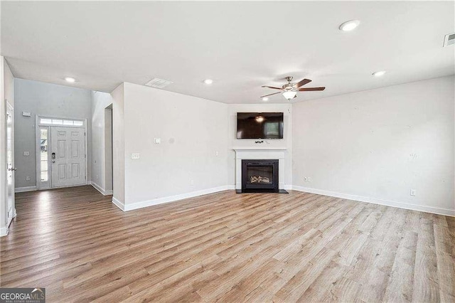 unfurnished living room with visible vents, baseboards, light wood-style floors, and a ceiling fan