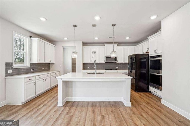 kitchen featuring appliances with stainless steel finishes, light countertops, light wood-type flooring, and a sink