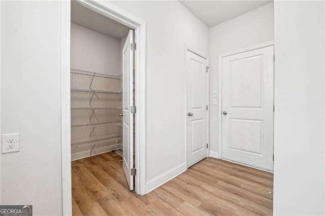 hall with light wood-style flooring and baseboards
