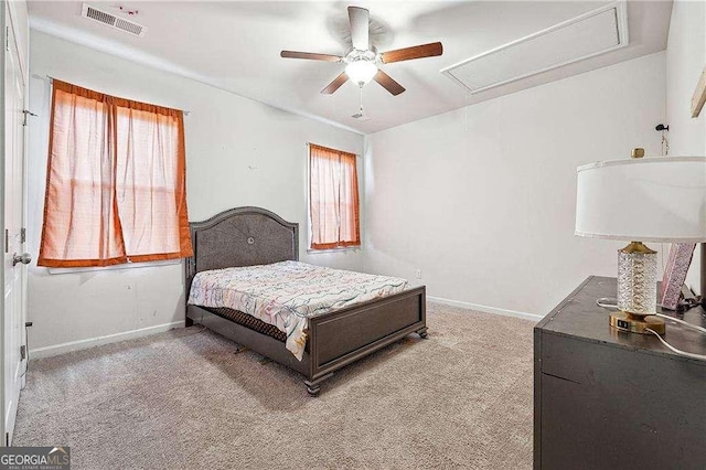carpeted bedroom with visible vents, baseboards, attic access, and ceiling fan