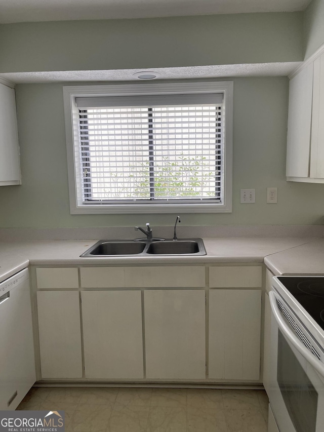 kitchen featuring a sink, white appliances, light countertops, and white cabinetry