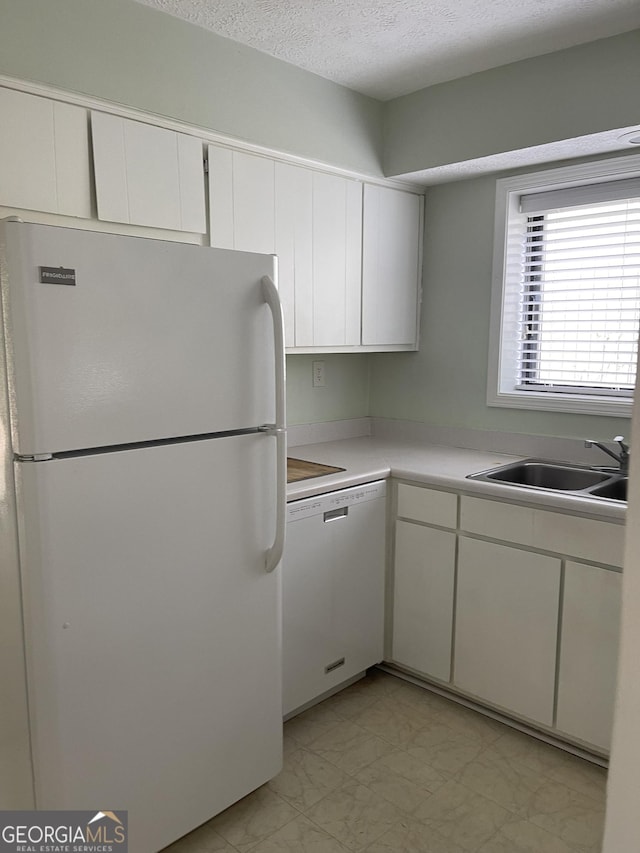 kitchen with white appliances, a sink, light marble finish flooring, white cabinetry, and light countertops