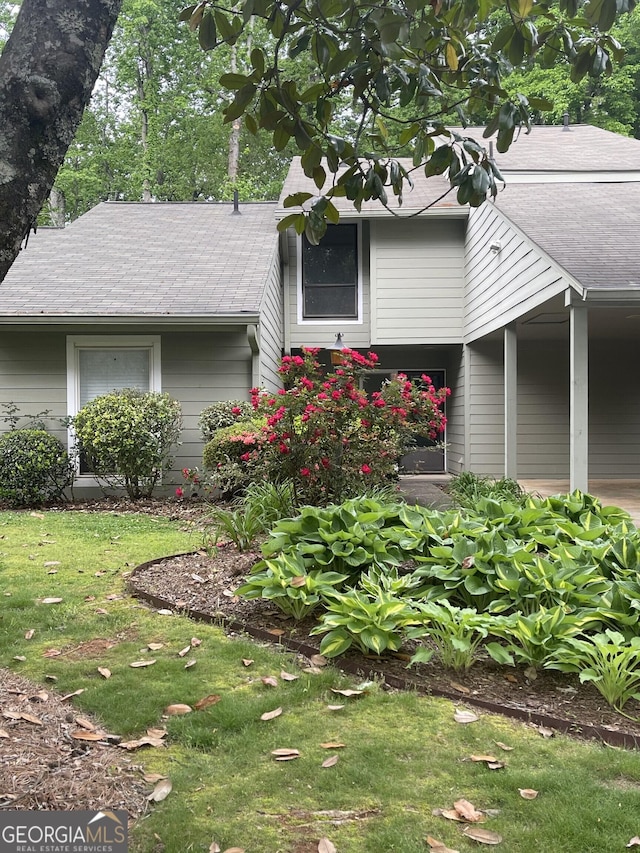 view of front facade with a front lawn and roof with shingles
