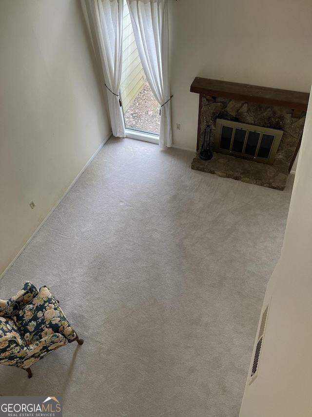 unfurnished living room featuring carpet and a stone fireplace