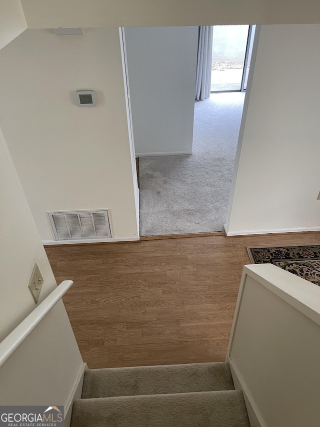 staircase featuring wood finished floors, vaulted ceiling, and carpet flooring