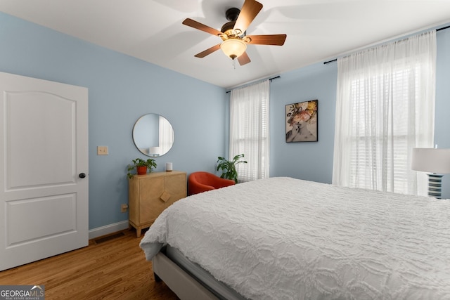 bedroom featuring visible vents, multiple windows, ceiling fan, and wood finished floors