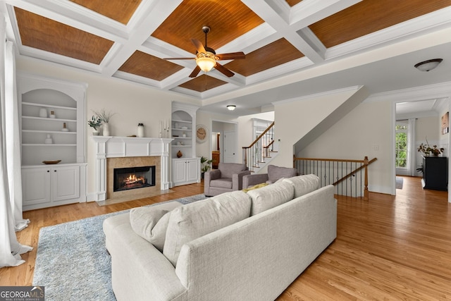 living area featuring built in shelves, light wood-type flooring, and a ceiling fan