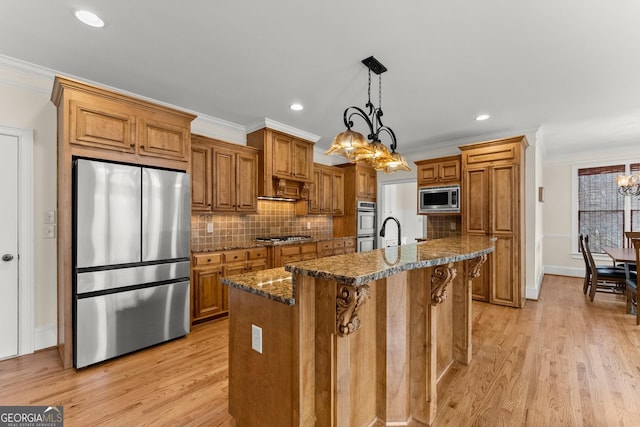 kitchen with brown cabinetry, a center island with sink, stainless steel appliances, and crown molding