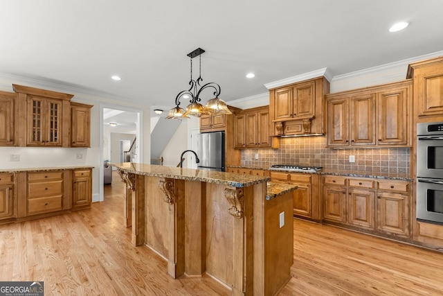 kitchen with brown cabinetry, light wood-type flooring, stainless steel appliances, and crown molding