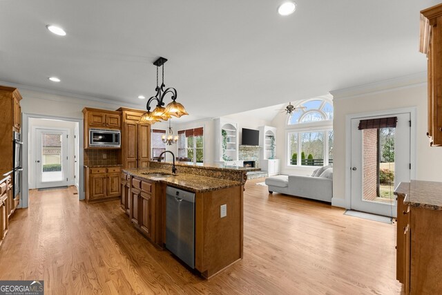 kitchen with a chandelier, a fireplace, brown cabinetry, stainless steel appliances, and a sink