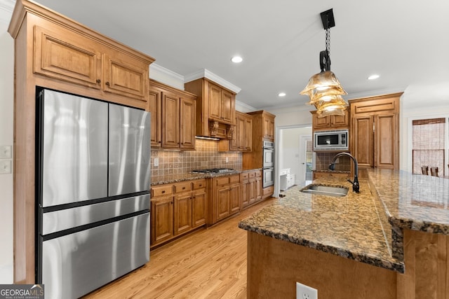 kitchen with decorative backsplash, light wood finished floors, appliances with stainless steel finishes, and a sink