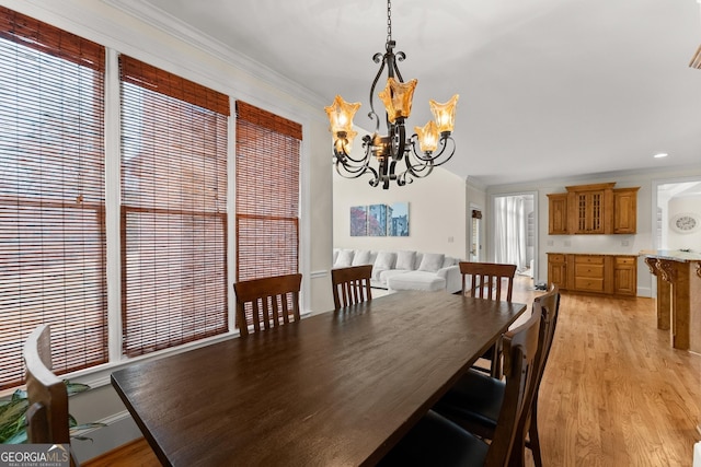 dining area featuring light wood-style flooring, a chandelier, and ornamental molding