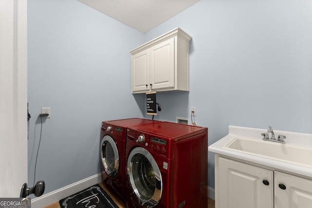 laundry room featuring a sink, baseboards, cabinet space, and washer and clothes dryer