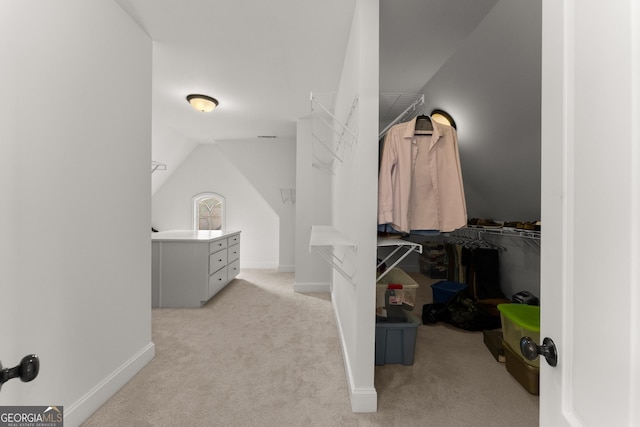 spacious closet with light carpet and vaulted ceiling