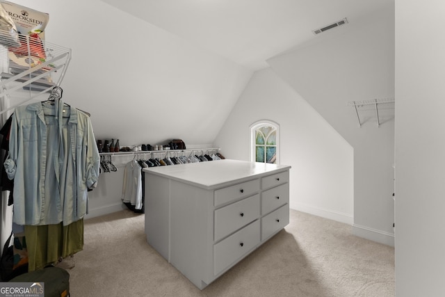 walk in closet featuring visible vents, lofted ceiling, and light colored carpet