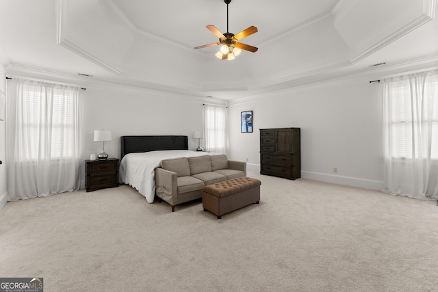 carpeted bedroom with a tray ceiling, multiple windows, crown molding, and baseboards