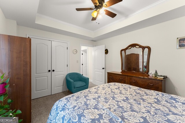 carpeted bedroom featuring a closet, a raised ceiling, a ceiling fan, and crown molding