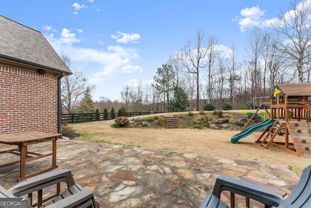 view of patio with a playground and fence