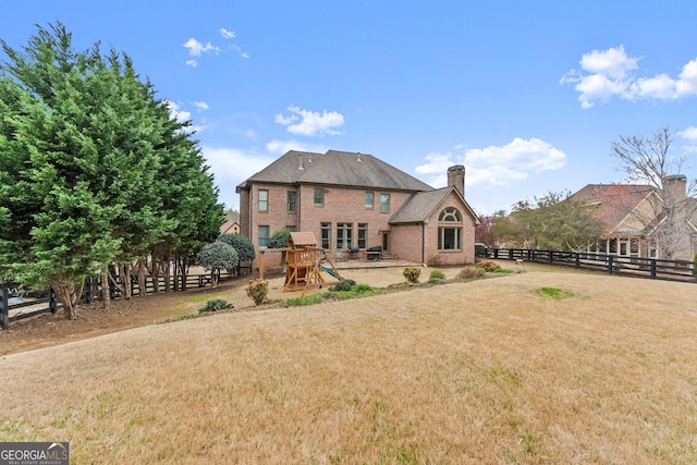 back of house featuring brick siding, fence, a chimney, a yard, and a patio