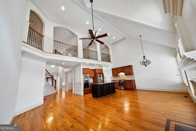 1372 Buckingham Ct, Watkinsville, GA 30677 - living area with high vaulted ceiling, stairway, light wood-style flooring, baseboards, and ceiling fan with notable chandelier