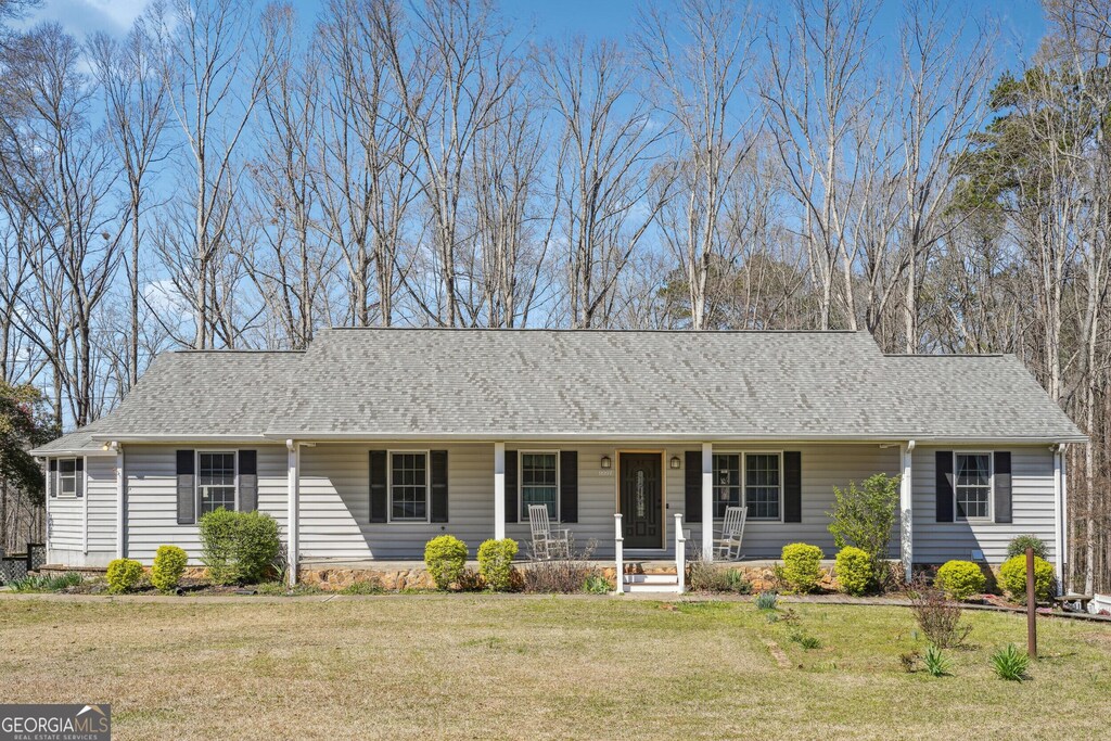 ranch-style home featuring a front yard, a porch, and roof with shingles