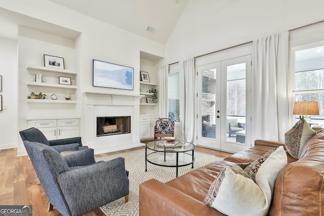 living room with french doors, visible vents, light wood-style floors, and built in shelves