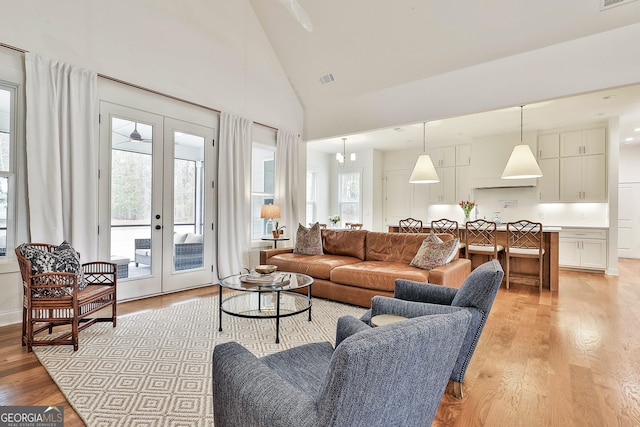 living room featuring a wealth of natural light, light wood-style flooring, and french doors