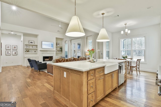 kitchen featuring light countertops, a sink, light wood finished floors, visible vents, and dishwasher