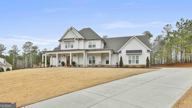 modern farmhouse featuring covered porch, roof with shingles, board and batten siding, and a front yard