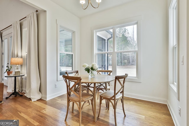 dining space with an inviting chandelier, baseboards, and light wood-type flooring