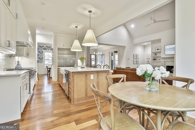 kitchen featuring an island with sink, light countertops, light wood-style flooring, and lofted ceiling