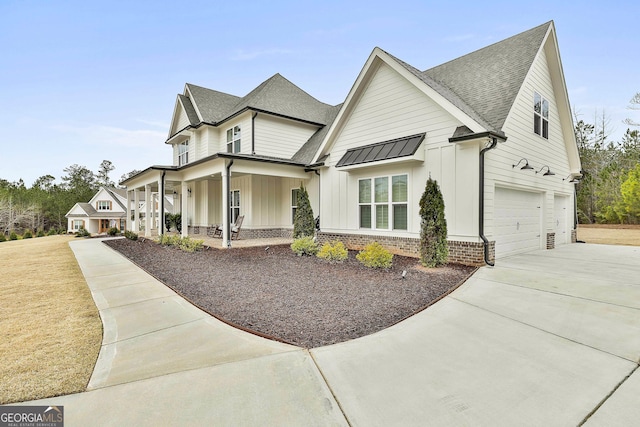 modern farmhouse style home featuring concrete driveway, board and batten siding, brick siding, a porch, and a garage