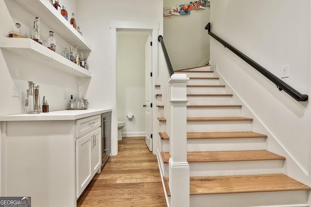 staircase featuring a dry bar and wood finished floors