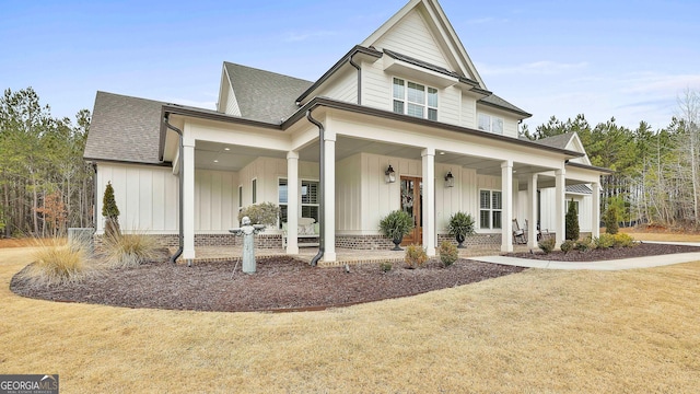 view of front of house featuring a shingled roof, a front lawn, board and batten siding, and a porch