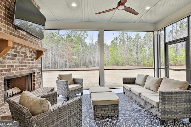 sunroom / solarium featuring an outdoor living space with a fireplace, a baseboard heating unit, and a ceiling fan