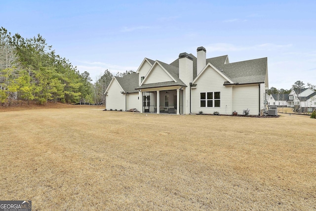 view of front of house featuring a front yard, roof with shingles, and a chimney