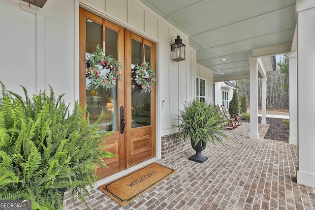 entrance to property with french doors, a porch, and board and batten siding