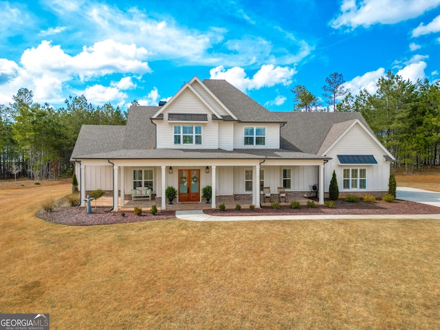 view of front facade with a front yard, board and batten siding, a shingled roof, french doors, and a porch