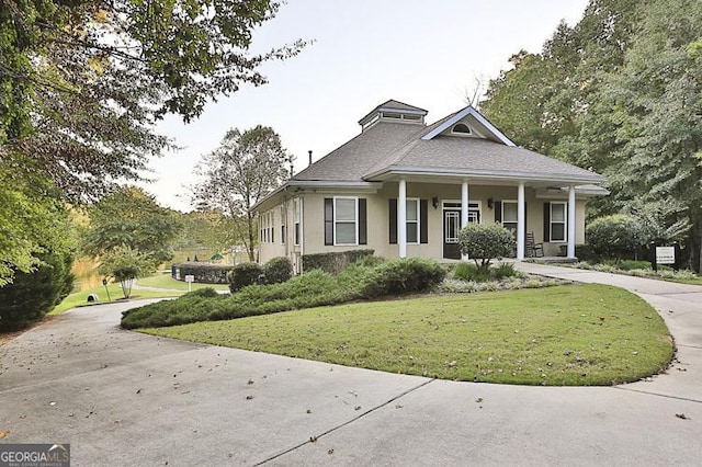 view of front of property featuring driveway, covered porch, a front lawn, and stucco siding