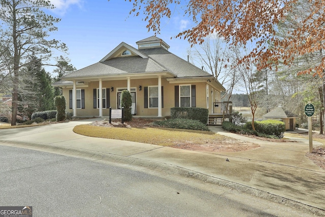 view of front of property with covered porch, concrete driveway, stucco siding, and roof with shingles