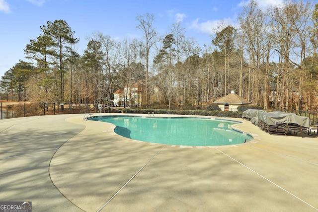 community pool with a patio area and fence