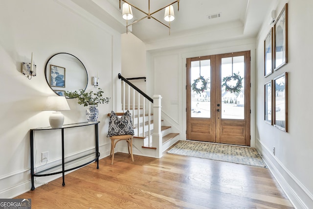 foyer entrance with visible vents, baseboards, stairs, wood finished floors, and french doors