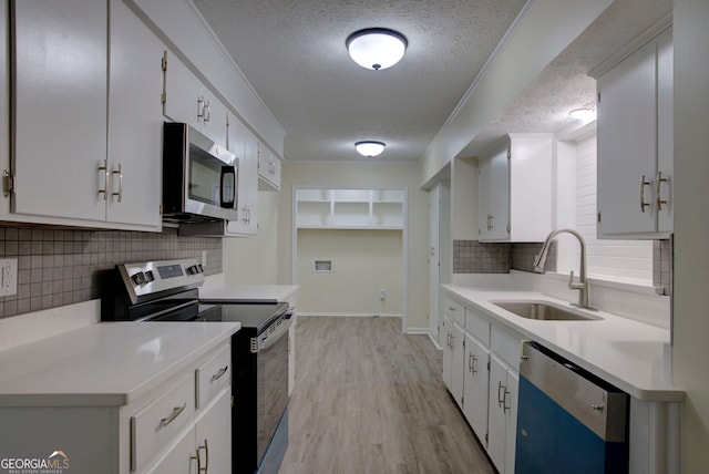 kitchen featuring appliances with stainless steel finishes, a sink, light countertops, a textured ceiling, and decorative backsplash